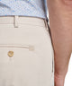 Men's light beige performance pants close-up: gold button and front pocket
