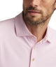 Pink geo-print mesh polo shirt front close-up with pointed collar and button placket.